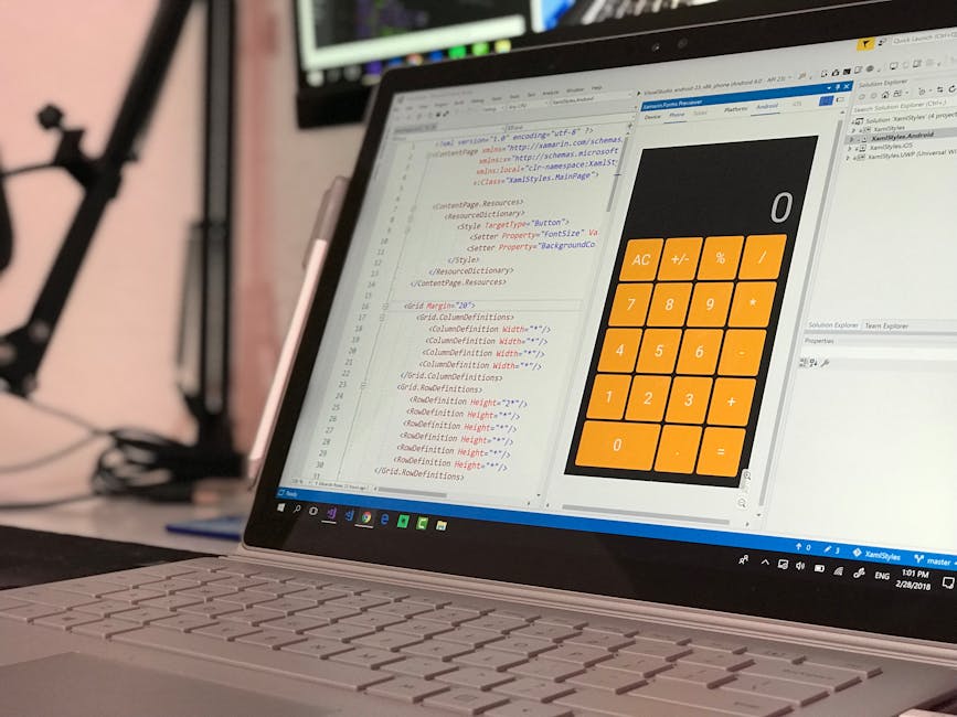 A close-up view of a laptop computer displaying a coding or programming interface on its screen. The screen shows colored code text on the left side and a large digital calculator with orange buttons